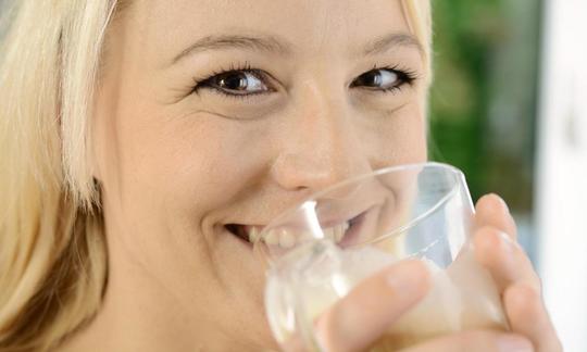 Woman drinking oat milk out of a glass.