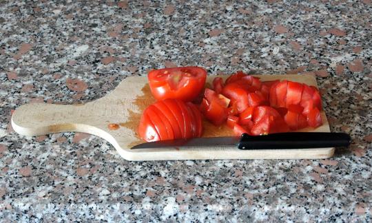 Geschnittene Tomaten auf Küchenbrett. Daneben liegt ein Messer.