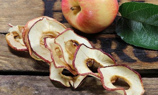 Anelli di mele, essiccati o essiccati, mela e foglia di mela dietro