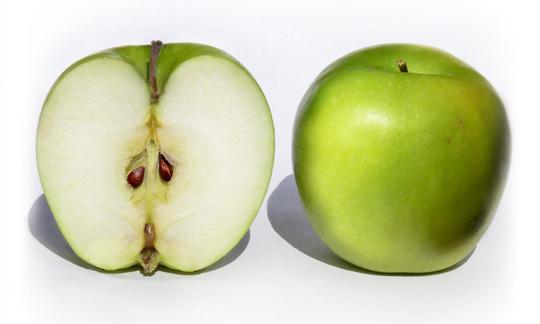 Frutas crudas, sin procesar: manzana, cruda, granny smith, con piel (Malus domestica). Due mele crude della varietà Granny Smith, quella sul taglio a sinistra. Malus domestico