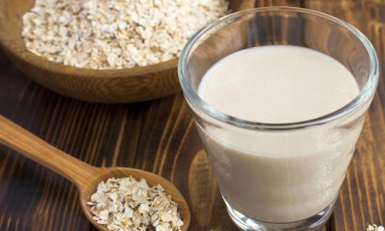 Raw vegan organic oat milk in a glass with organic oat flakes around it. Raw vegan organic oat milk in a glass with organic oat flakes around it.