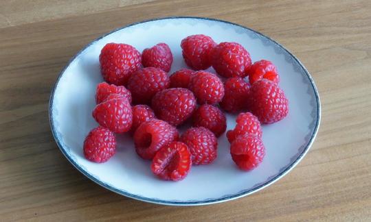 В ягодах малины удивительно гармонично сочетаются цвет, аромат и вкус. Из-за содержащихся в ней веществ, в древности её использовали как лекарственное растение. Тарелка с малиной на деревянном столе.