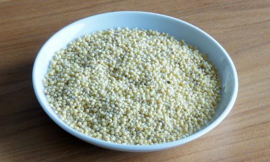 Plato de cerámica con mijo de oro crudo. Esto significa semillas de mijo liberadas del caparazón.