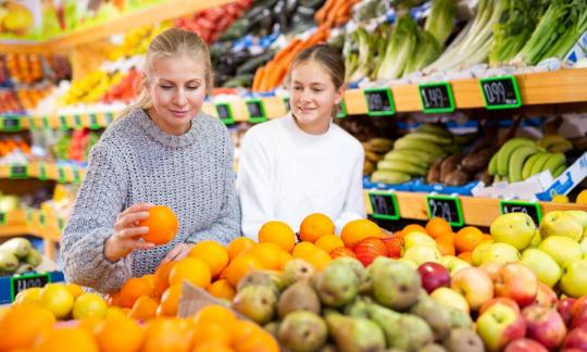 Mother and daughter choosing and buying fruits and vegetables.