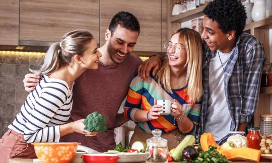 Freunde, die mit Spassgefühl eine vegane Mahlzeit zubereiten.