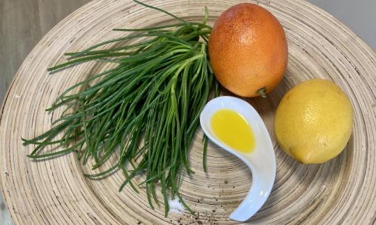 Bild der bereitgestellten Zutaten für "Agretti all´arancia" auf brauner Unterlage.