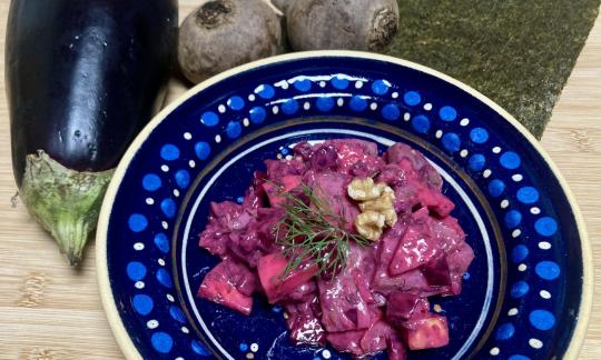 Rezeptbild vom fertigen veganen "Heringssalat" mit Aubergine, Apfel und Walnüssen auf blauem Teller.