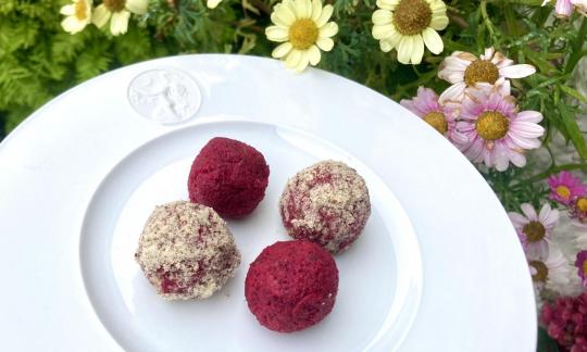 Изображение рецепта готовых «Сладких сыроедческих энергетических шариков со свеклой» на белой тарелке.