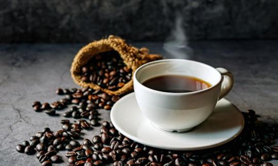 Kaffee - Coffea arabica - in weisser Porzellantasse, Kaffeebohnen drum herum liegend. Kaffee - Coffea arabica - in weisser Porzellantasse, Kaffeebohnen drum herum liegend.