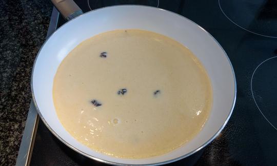 Masa batida lista para preparar «Tortitas austriacas Kaiserschmarrn con arándanos» en la sartén.