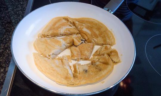 Tortitas austriacas *Kaiserschmarrn* con arándanos. Tortita preparada y dividida en la sartén.