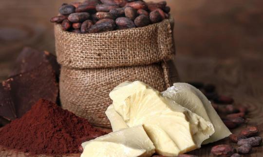 Cocoa butter pieces in front of a sack with cocoa beans, cocoa powder and chocolate on the left. Cocoa butter pieces in front of a sack with cocoa beans, cocoa powder and chocolate on the left.