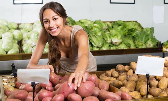 Two types of potatoes—Solanum tuberosum: A seller is reaching for red potatoes. There are many varieties to choose from depending on the use. Two types of potatoes—Solanum tuberosum: A seller is reaching for red potatoes. There are many varieties to choose from depending on the use.