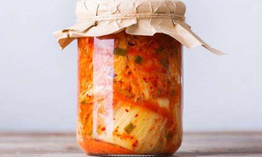 Домашний традиционный корейский салат кимчи из капусты в стеклянной банке на деревянном столе. Домашний традиционный корейский салат кимчи из капусты в стеклянной банке на деревянном столе.