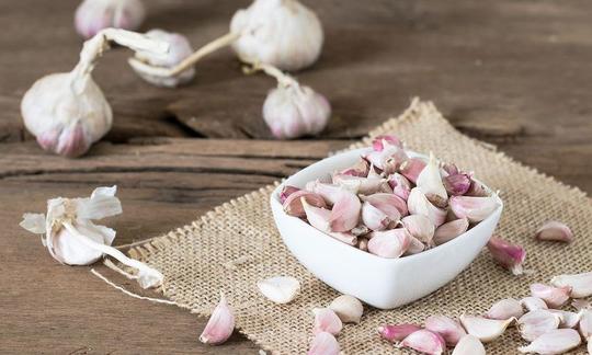 Garlic, raw - Allium sativum: foreground bowl of garlic cloves, background whole onions.