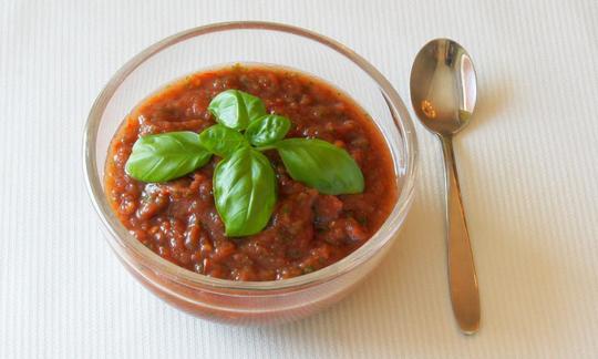 Fertig zubereitete Tomatensauce mit Tamarinde, angerichtet in einer Schüssel und garniert mit Basilikum.