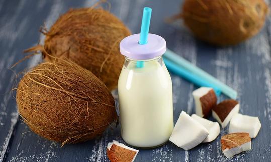 Coconut milk is pulp mashed with water, here in bottle, next to coconut and pieces.