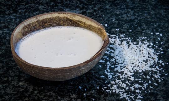 Kokosmilch in einer Kokosschale: Kokosmilch besitzt von Natur aus einen hohen Fettanteil und lässt sich auch von Hand einfach selber herstellen. Kokosmilch in einer Kokosschale: Kokosmilch besitzt von Natur aus einen hohen Fettanteil.