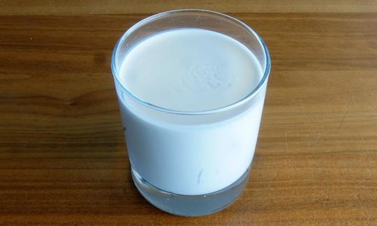 Rohe Kokosmilch in einem Glas: Aufgrund ihres Fettgehaltes, vor allem dem hohen Anteil gesättigter Fettsäuren, gilt die Kokosmilch als grosser Energielieferant. Kokosmilch ist Fruchtfleisch mit Wasser püriert, hier in Trinkglas.