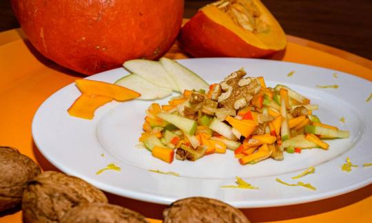 Готовый «Салат из сырой тыквы с яблоком, грушей и грецкими орехами» на тарелке.