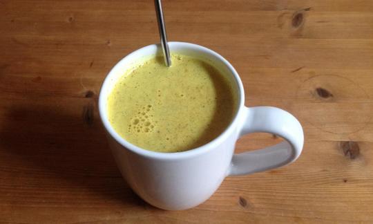 Warming Raw Energy Drink with Ginger and Turmeric, served in a cup.