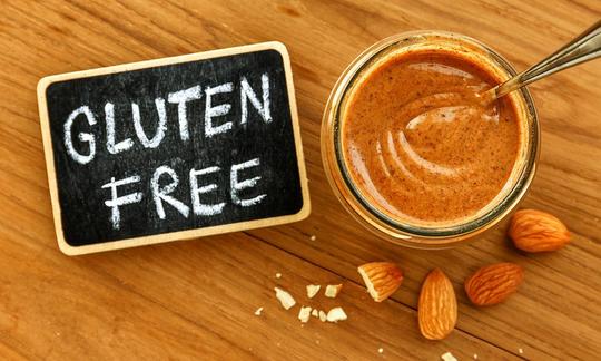 Selbst hergestellte Mandelbutter in einem Glasbehälter, daneben Tafel mit Schriftzug "gluten free". Selbst hergestellte Mandelbutter in einem Glasbehälter, daneben Tafel mit Schriftzug "gluten free".