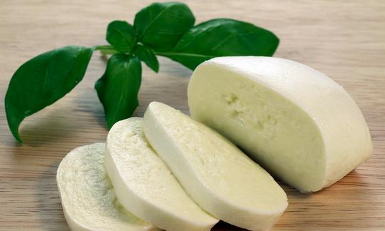 Mozzarella di verdure a base di anacardi, affettata, con foglie di basilico dietro. Mozzarella di verdure a base di anacardi, affettata, con foglie di basilico dietro.