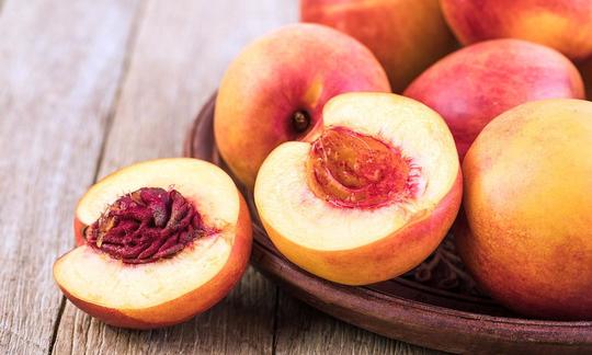 Fresh nectarines, one cut open - Prunus persica var. Nucipersica.