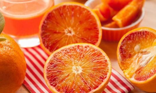 Orange, raw, with peel (Citrus sinensis): oranges cut in half, and in the backgroud orange juice. Orange, raw, with peel (Citrus sinensis): oranges cut in half, and in the backgroud orange juice.