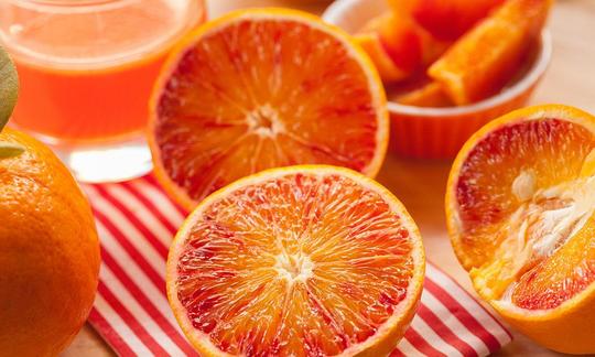 Orange, roh, mit Schale - Citrus sinensis: aufgeschnittene Früchte, dahinter Orangensaft. Orange, roh, mit Schale - Citrus sinensis: aufgeschnittene Früchte, dahinter Orangensaft.