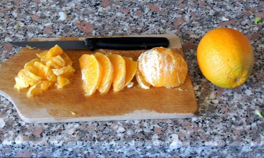 На разделочной доске справа налево размещены: почищенный апельсин, дольки апельсина (филе) и, наконец, кусочки апельсина.
