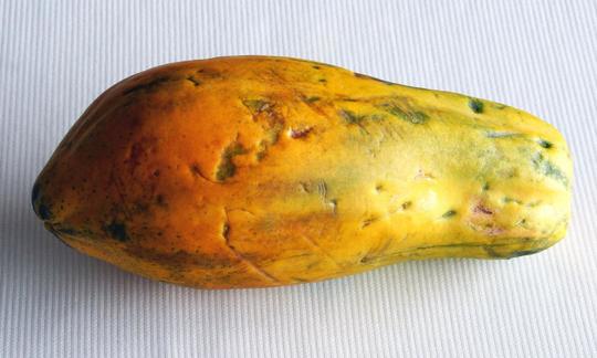 Papaya sobre un plato: la pulpa de la papaya es afrutada y dulce. Las semillas son comestibles y su sabor es picante. Papaya sobre un fondo blanco: La pulpa de papaya tiene un sabor jugoso y dulce.