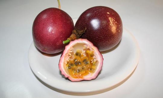 Auf einem Teller ausgelegte Passionsfrüchte mit halbierter Frucht im Vordergrund. Auf einem Teller ausgelegte Passionsfrüchte mit halbierter Frucht im Vordergrund.