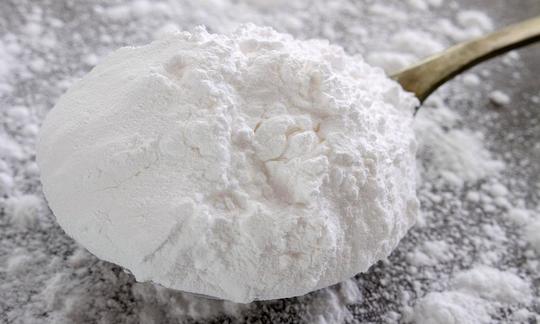 Powdered sugar piled on a ladle, powdered sugar scattered around it.
