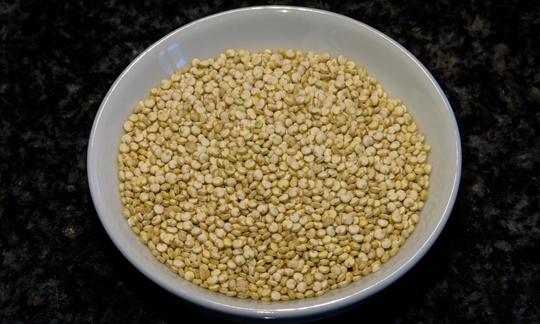 Quinua cocida en un bol: la quinua no es un cereal sino una quenopodiácea y por lo tanto, no contiene gluten. Quinoa, cruda in una ciotola. La quinoa in realtà non è un chicco, ma un pseudo-chicco.
