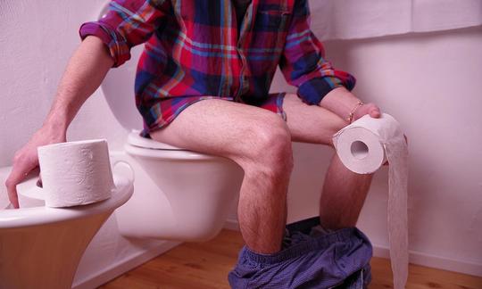 Uomo con problemi digestivi in bagno per evacuare.