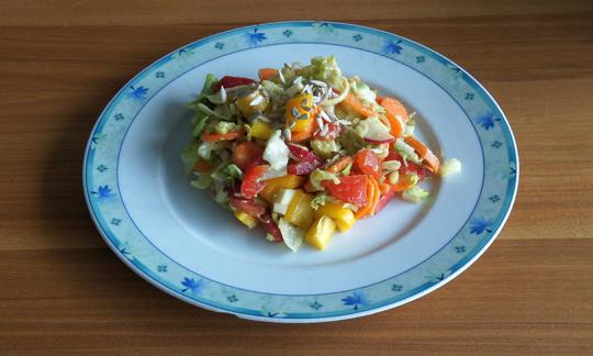 Готовый "Салат из сырых овощей с заправкой из лимона и авокадо", украшенный подсолнечными семечками.