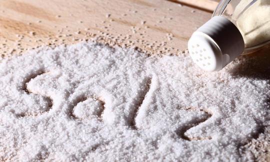 Salz bzw. Tafelsalz ausgestreut mit Salzstreuer auf Holztisch. Allgemein salzen wir viel zu viel - mit gesundheitlichen Konsequenzen! Salz bzw. Tafelsalz ausgestreut mit Salzstreuer auf Holztisch. Allgemein salzen wir viel zu viel.