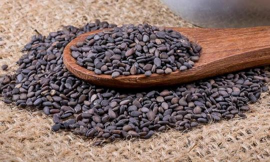 Деревянная ложка с кунжутом, чёрным - Sesamum indicum - снимок крупным планом. Деревянная ложка с кунжутом, чёрным - Sesamum indicum - снимок крупным планом.