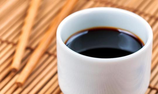 Soy sauce (shoyu) in white cup without handle on bamboo mat. Soy sauce (shoyu) in white cup without handle on bamboo mat.