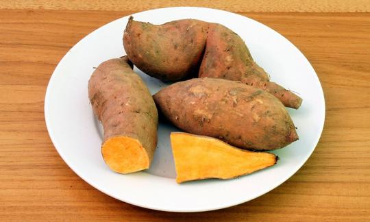 Raw sweet potatoes on a plate. Sweet potatoes are rich in protein, minerals, and vitamins. The peel can also be eaten. Raw sweet potatoes on a plate: The sweet potato is rich in proteins and minerals.