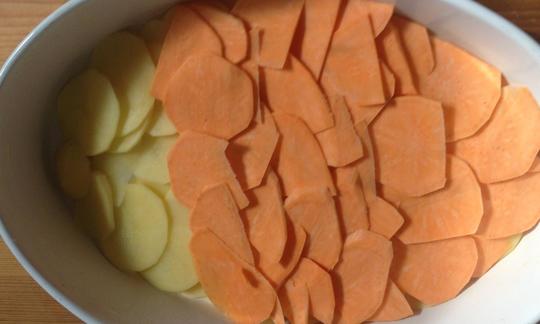 Potato slices for the "sweet potato gratin with rosemary and soy cream" are layered alternately on top of each other in the prepared oven dish.