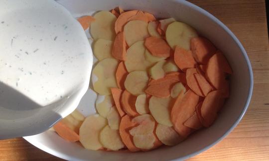 Versare la crema di soia speziata sopra le patate dolci per preparare "Patate dolci gratinate con rosmarino e crema di soia".