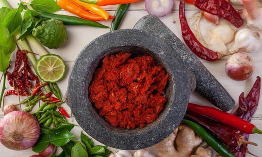 Red Thai curry paste with ginger and kaffir lime leaves - ingredients next to it.