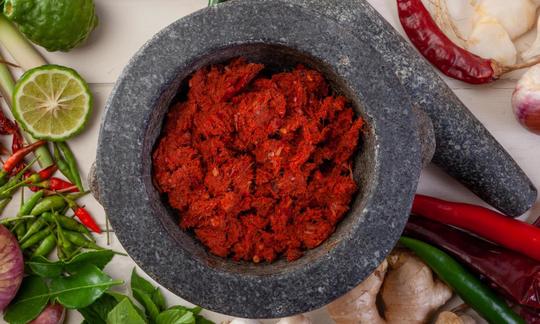 Red Thai curry paste with ginger and kaffir lime leaves and some ingredients alongside.