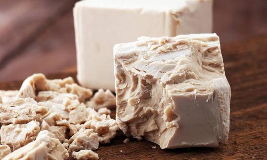 Baked yeast crumbled and yeast block for baking in the background. Baked yeast crumbled and yeast block for baking in the background.
