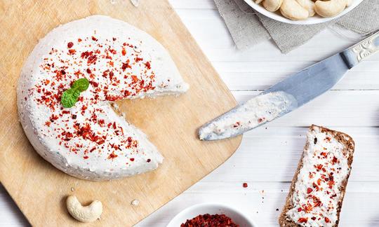 Кешью «сыр» с мисо и кокосовым маслом, нарезанный на кухонной доске.