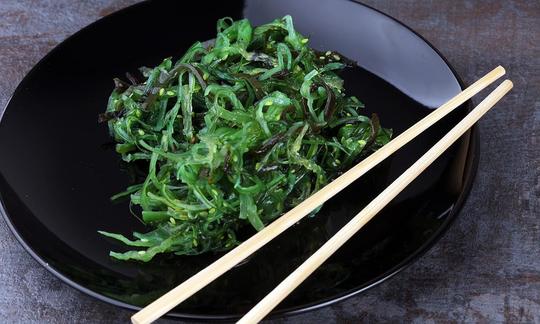 Wakame, roh - Undaria pinnatifida - fein geschnitten mit ein paar Sesam-Samen in schwarzem Teller. Wakame, roh - Undaria pinnatifida - fein geschnitten mit ein paar Sesam-Samen in schwarzem Teller.