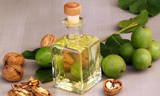 Olio di noce in una bottiglia di vetro, circondato da foglie di noce e noce con e senza uno strato esterno.