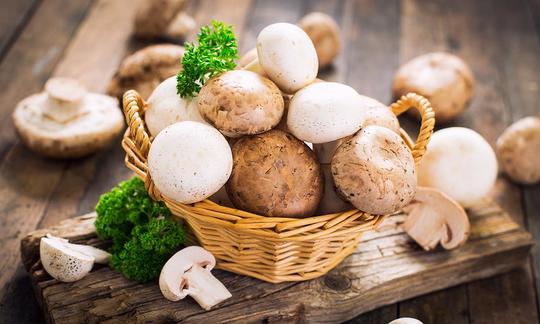 Funghi coltivati, commestibili crudi: cestini di vimini con funghi bianchi e marroni.